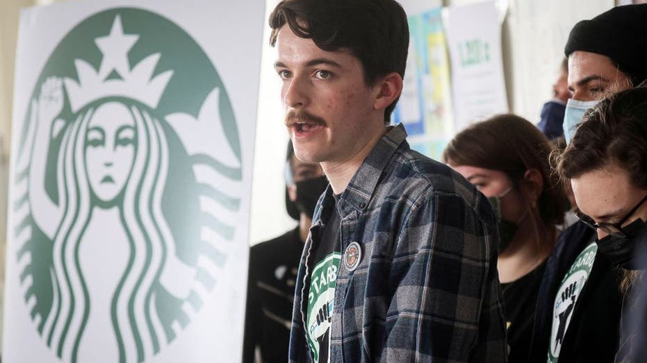 Starbucks worker with mustache with Starbucks logo banner in background