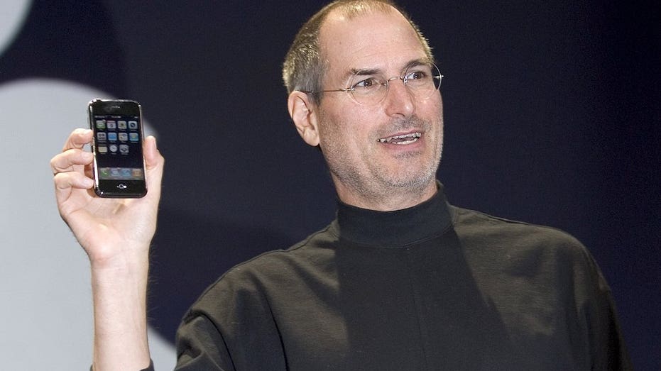 Steve Jobs holding the original iPhone