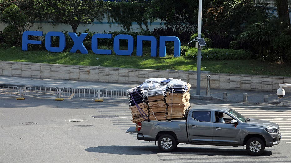 Truck with materials in the back drives in front of the Foxconn sign