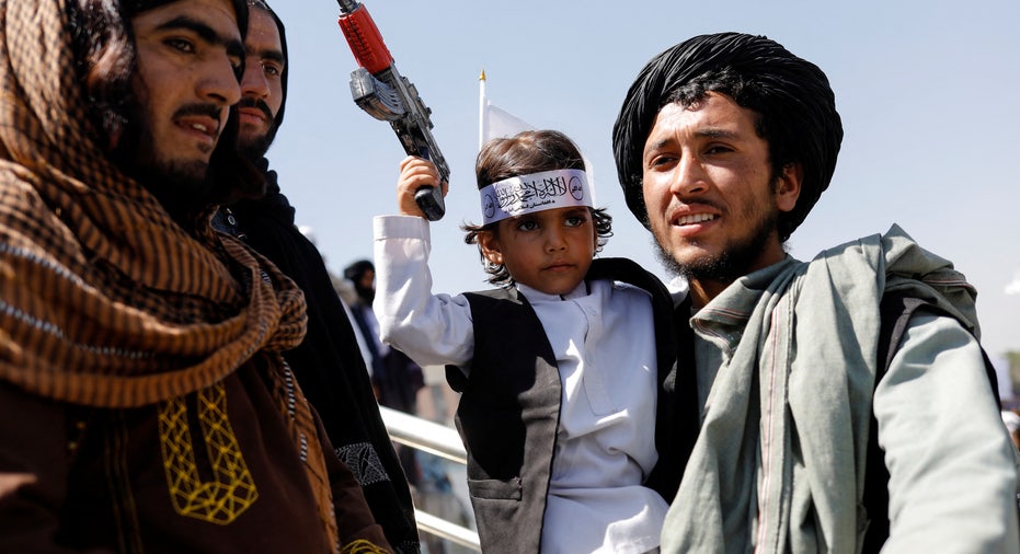 Taliban member holds his son on the first anniversary of the withdrawal of U.S. troops from Afghanistan