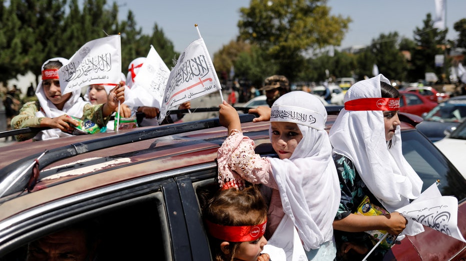 فتيات أفغانيات يرفعن أعلام الإمارات الإسلامية أثناء مشاركتهن في الذكرى الأولى لانسحاب القوات الأمريكية من أفغانستان