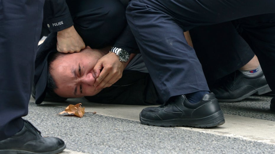 Police pin down and arrest a protester in Shanghai, China