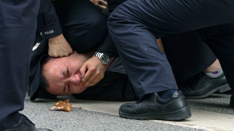 Police pin down and arrest a protester in Shanghai, China