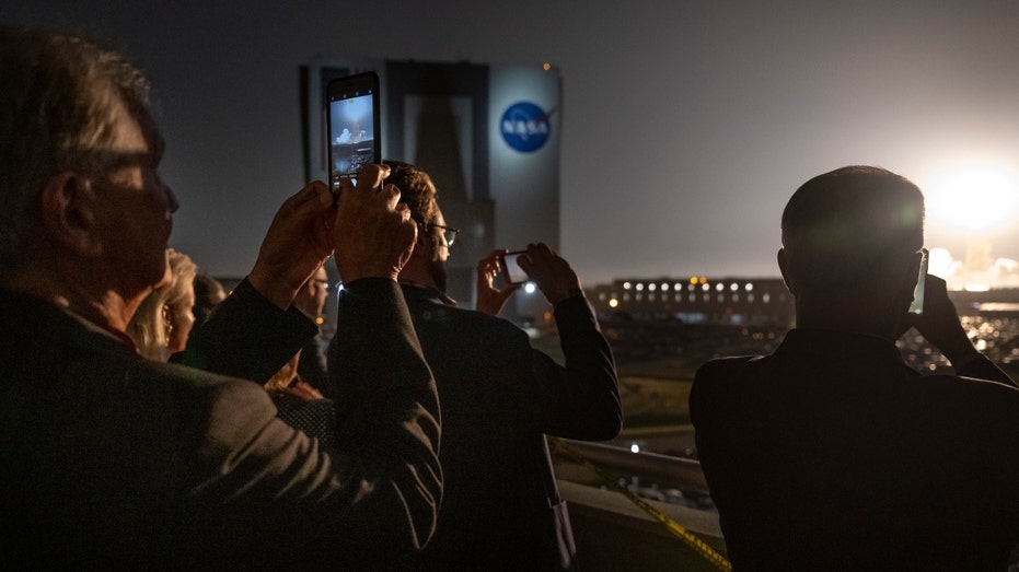 People watch as the Space Launch System rocket lifts off