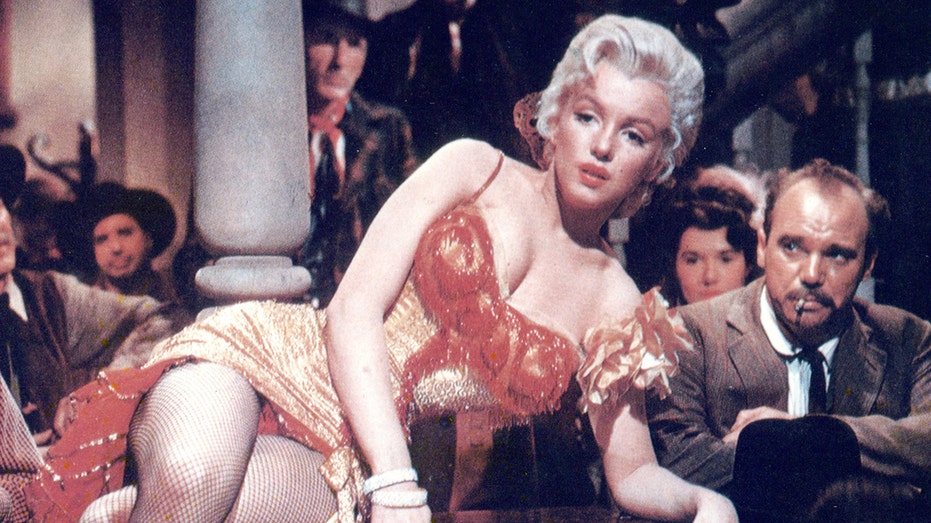 Marilyn Monroe reclining on a piano in a movie in a red dress