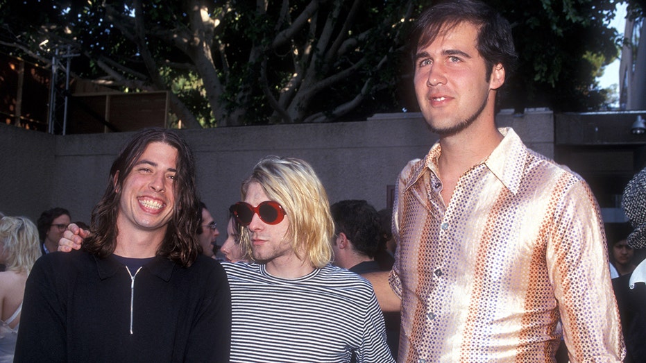 The members of Nirvana posing for a photographer on the red carpet