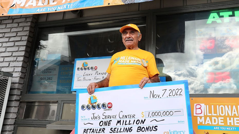 Business owner holds Powerball bonus check