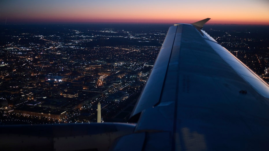 An airplane flies over the Washington Monument