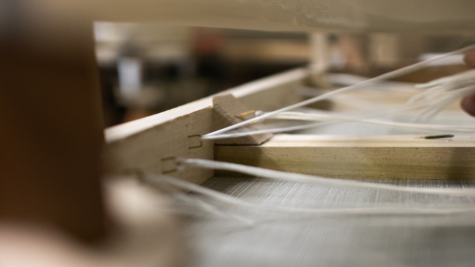 An employee prepares a sofa frame