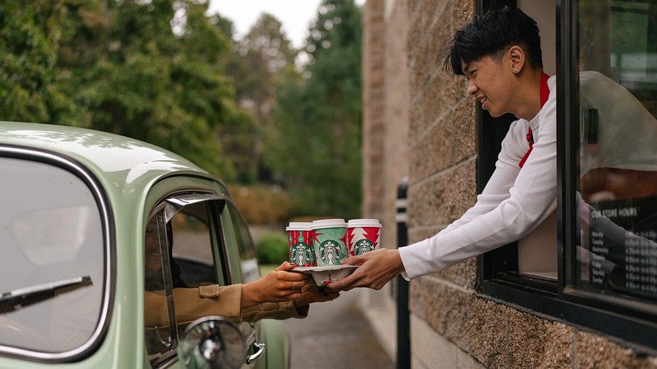 Starbucks barista handing drinks to drive-thru customer