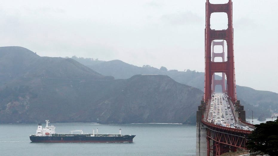 Oil tanker sails under bridge