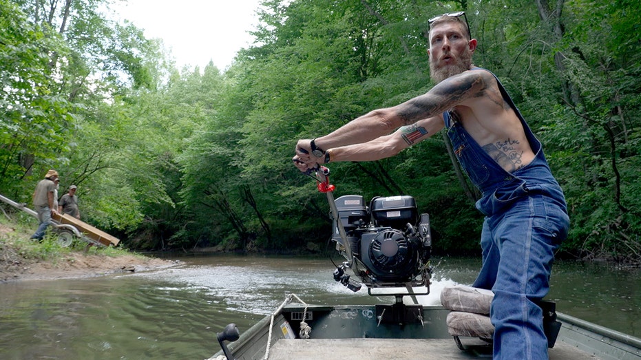 Josh Owens moving the propeller on his boat in the water.