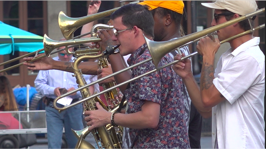 Male performers with trumpets and a saxophone performing