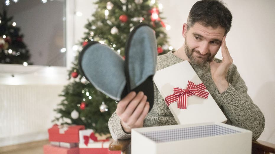 Man looks disappointed as he opens Christmas gift