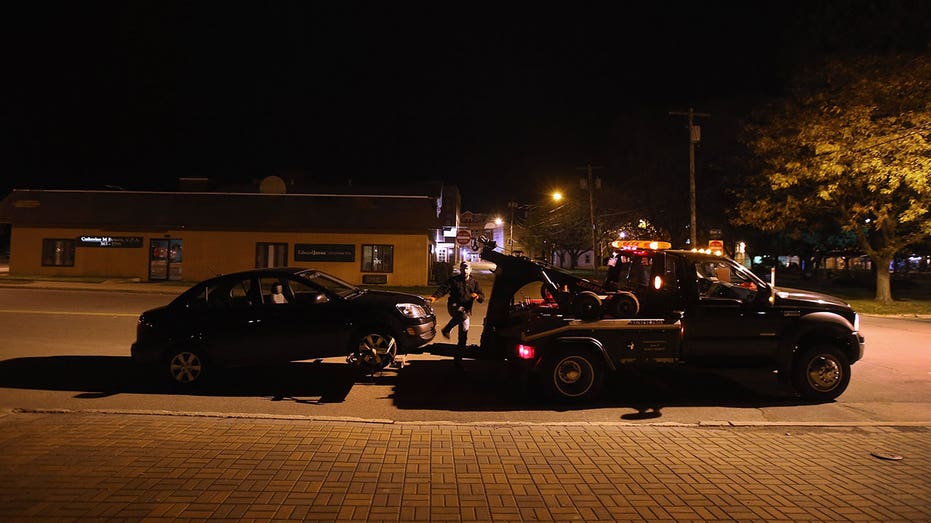 A car is attached to a two truck during nightime