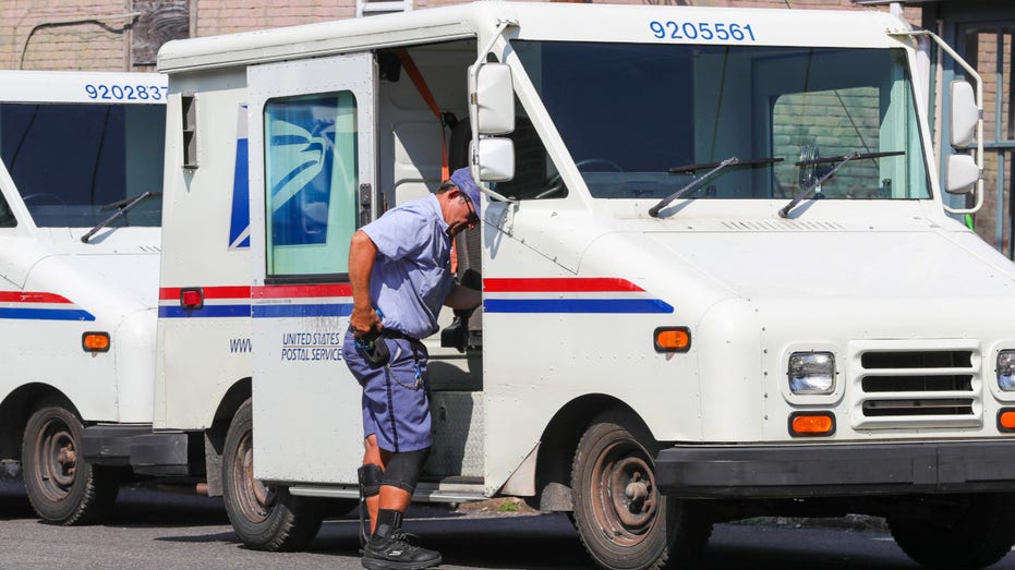 A United States postal worker enters his mail delivery truck