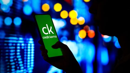 BRAZIL - 2022/04/06: In this photo illustration, a woman's silhouette holds a smartphone with the Credit Karma logo displayed on the screen. 