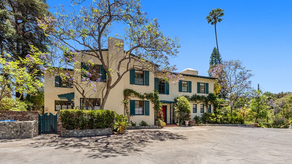 Exterior of Helen Mirren's yellow home in Los Angeles with green shutters and lots of ivy