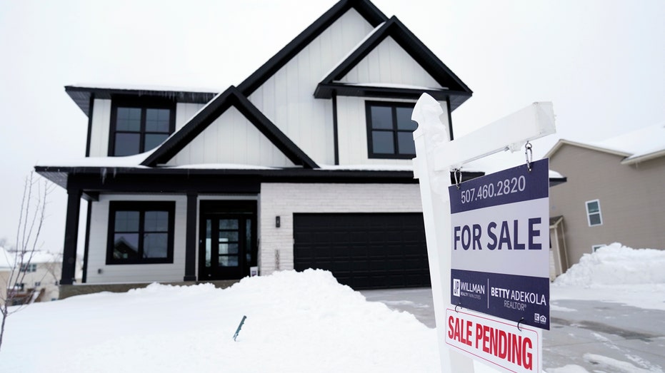 For sale sign with home in snow