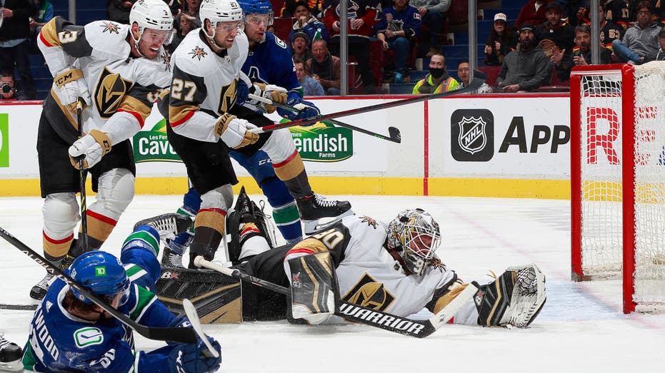 Lehner, R, diving to save the puck