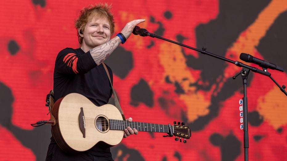 Ed Sheeran holding his guitar on stage