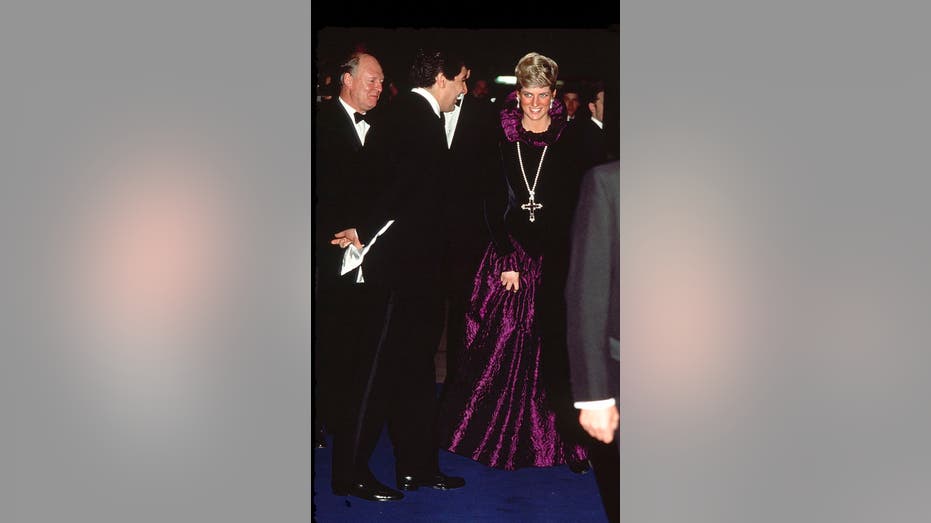 Princess Diana wears a purple dress and a cross necklace