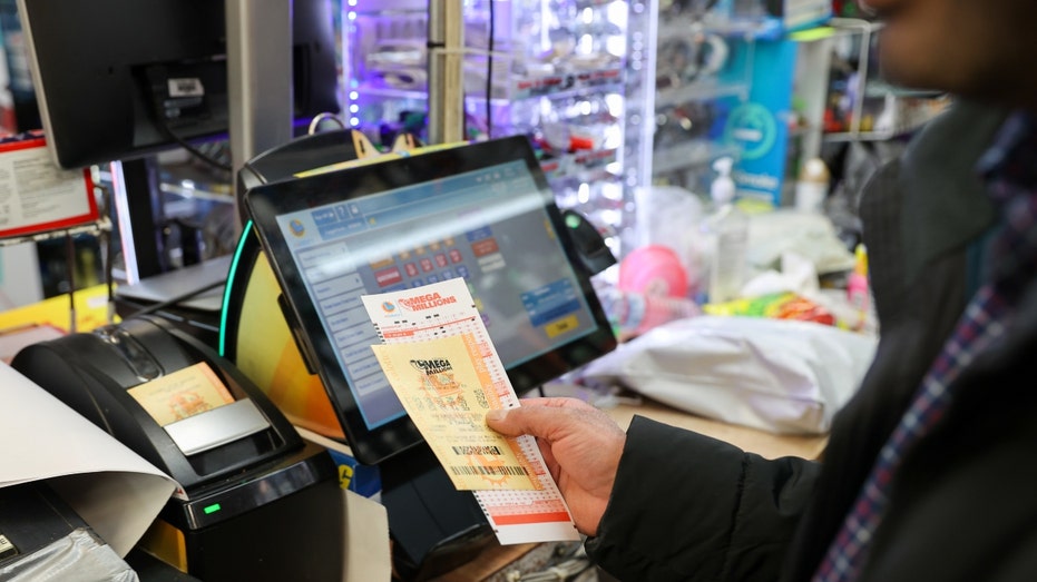 A cashier at a store hands a Mega Million lottery ticket to a player