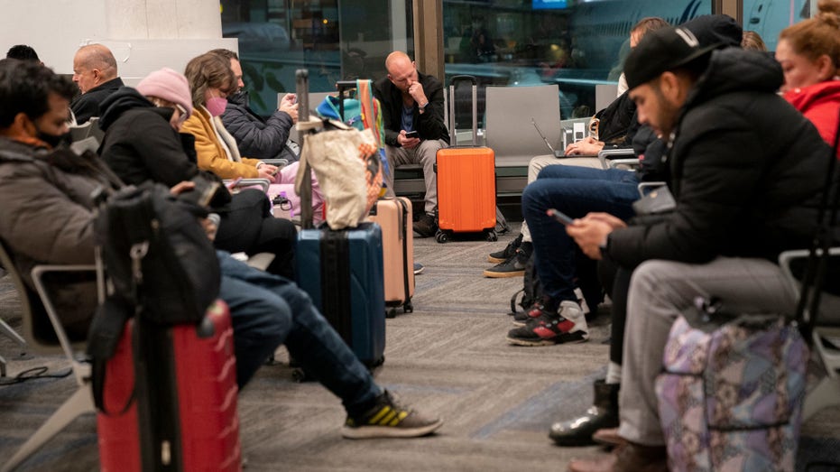 Travelers wait to hear if their flight will depart on time, at Los Angeles International Airport in Los Angeles, on January 11, 2023