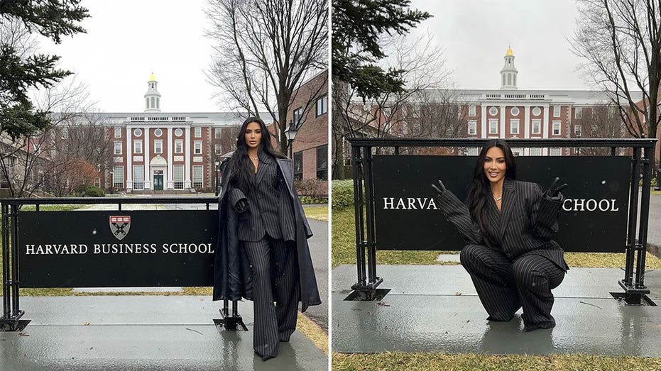 Kim Kardashian in a pinstripe black and white suit poses next to a sign that reads "Harvard Business School" split she crouches and does two peace signs in front of the sign