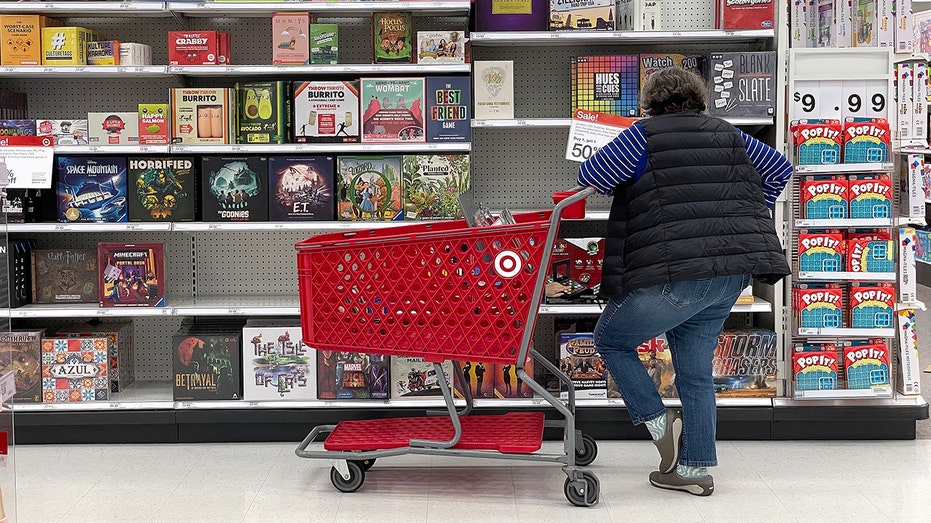 Woman stands with shopping cart in front of games