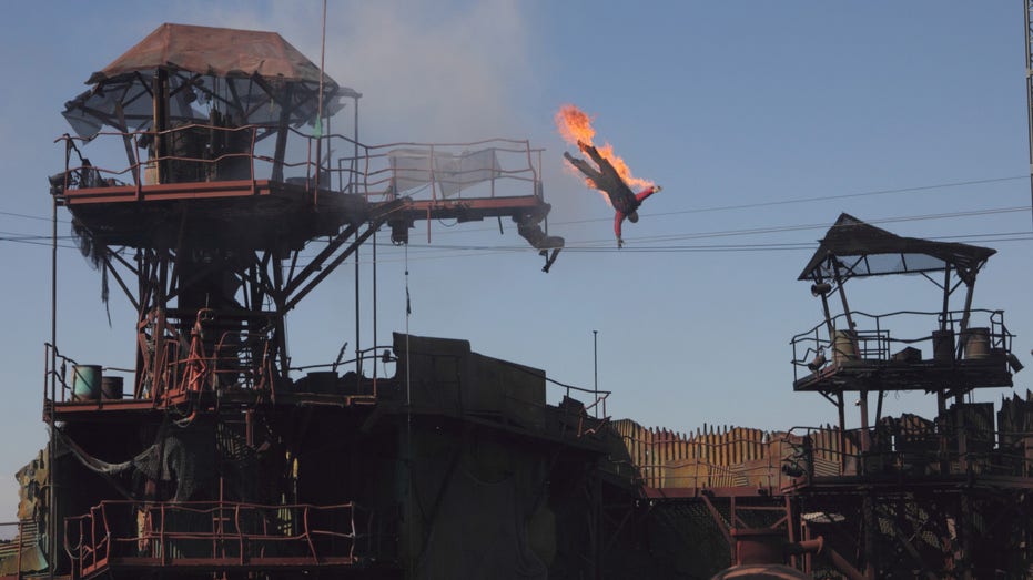 View of a stunt performer on fire and 'falling' from a platform during Universal Studios Hollywood's 'Waterworld: A Live Sea War Spectacular' show