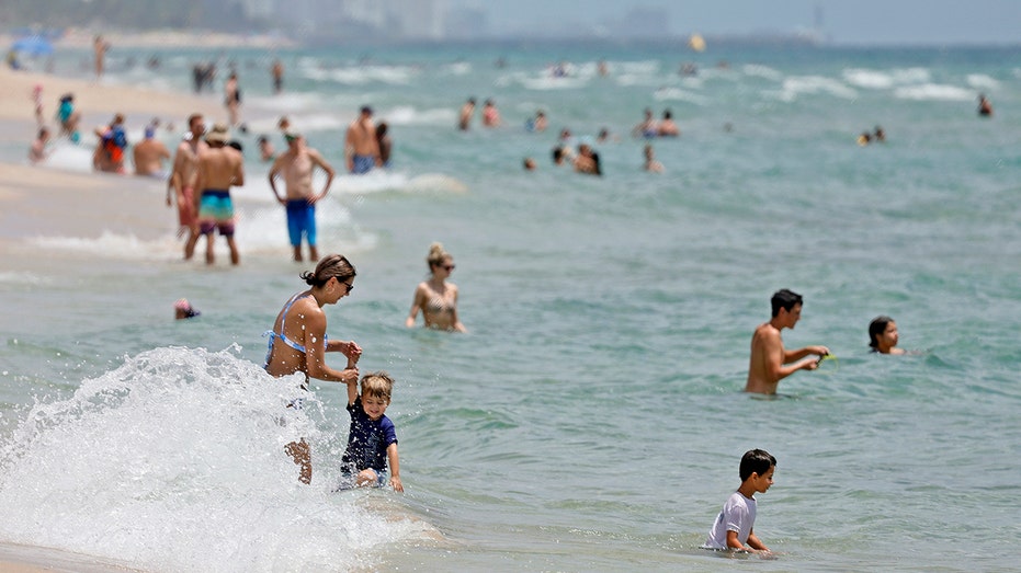 Beachgoers play in water and sand