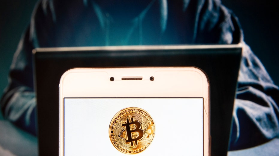 Hacker and bitcoin logo on smartphone