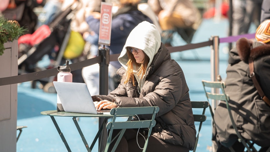 A person works on her laptop on the streets of New York City