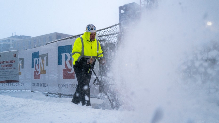 A worker with RJM Construction clears snow