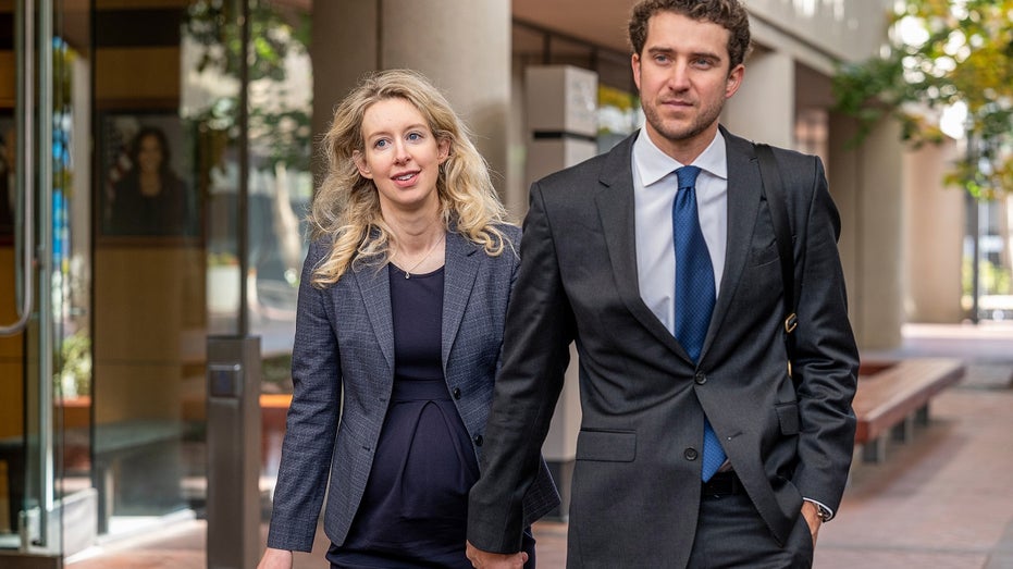 Elizabeth Holmes walks with partner Billy Evans