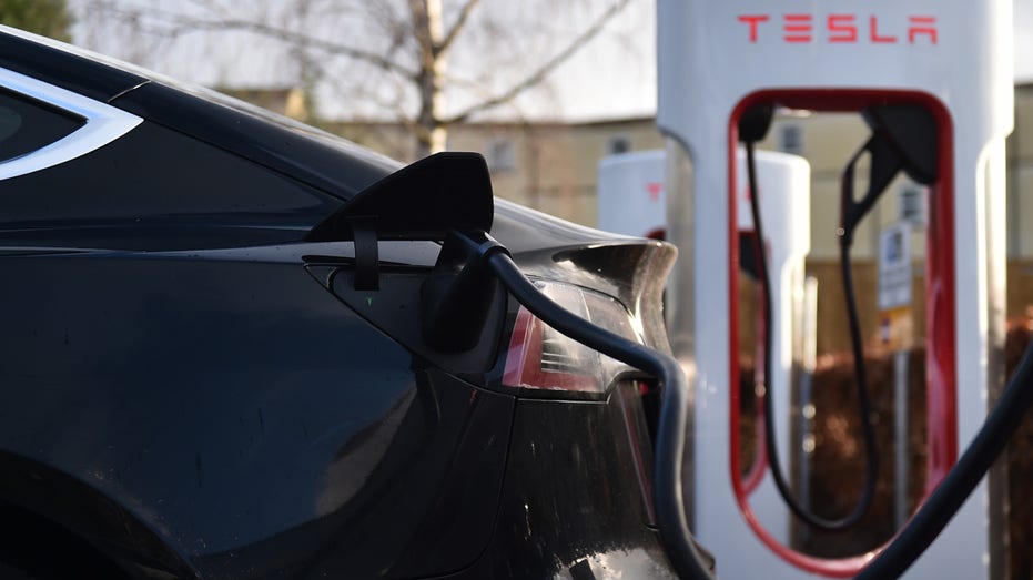 A Tesla car is charged at electric vehicle charging pod