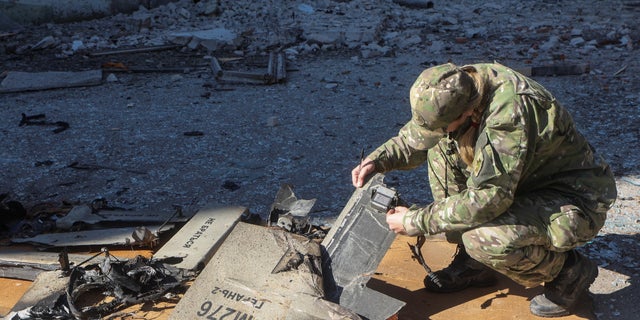 A police officer inspects parts of an unmanned aerial vehicle, which Ukrainian authorities deemed an Iranian-made suicide drone, in Kharkiv, Ukraine, on Oct. 6, 2022.