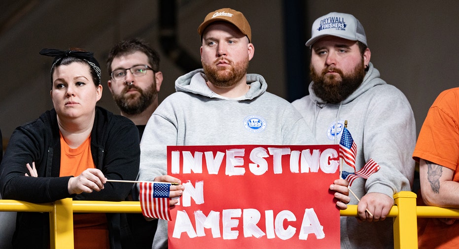 Workers hold sign during Biden speech