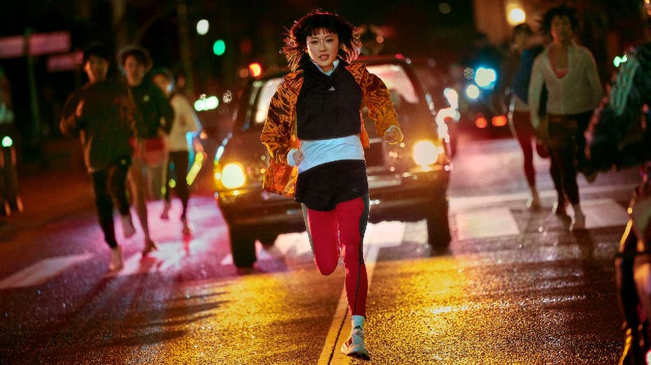 Group of women run together alongside cars