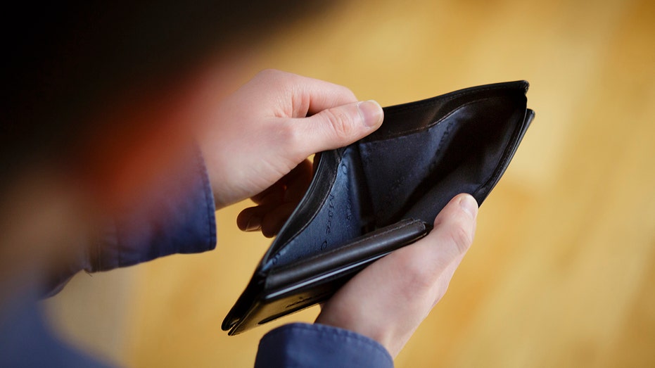 Man holds empty wallet open