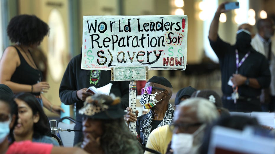 Los Angeles long-time resident Walter Foster, age 80, holds up a sign as the California Reparations Task Force meets to hear public input on reparations at the California Science Center in Los Angeles on Sept. 22, 2022.