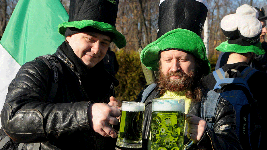 Two people holding mugs of green beer