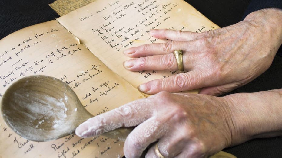 Person looks at cookbook with spoon in hand