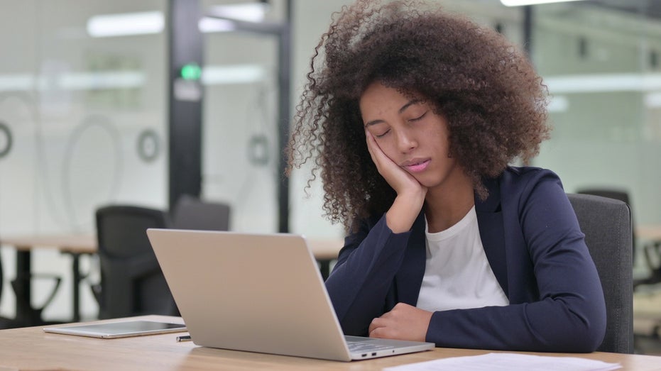young female worker sleeping at computer