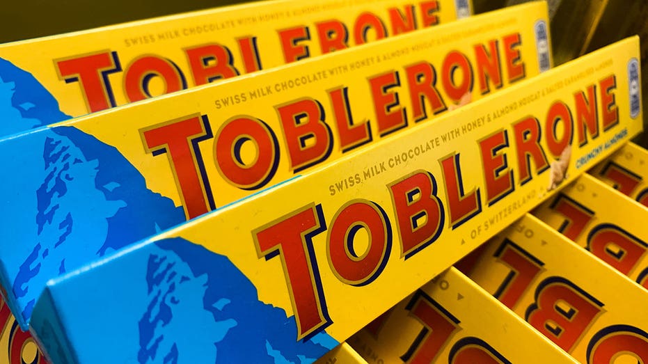 Three toblerone bars laid on top of other Toberlone bars in a store