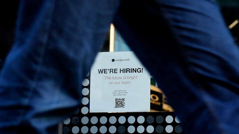 Man walks by we're hiring sign