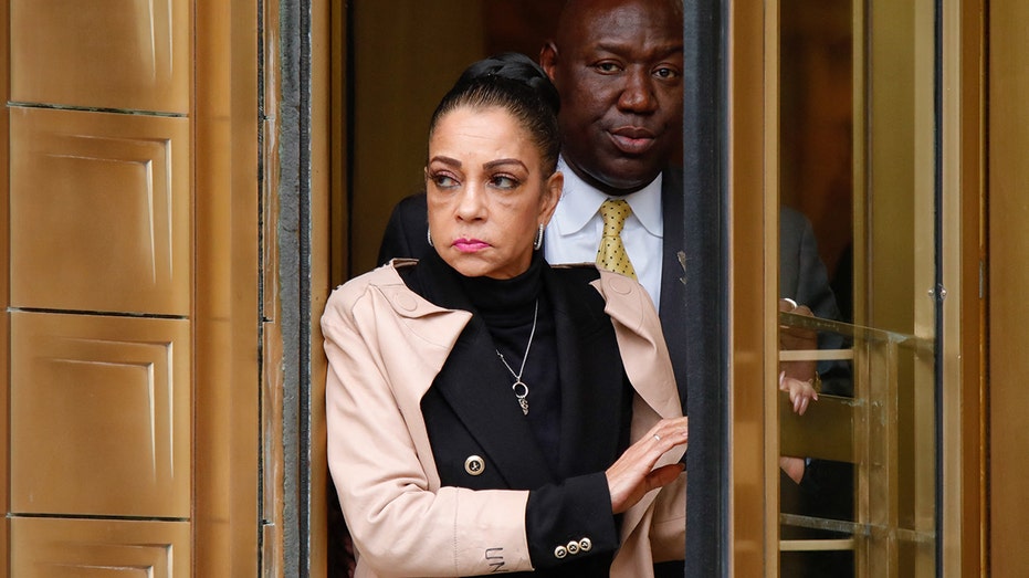 Kathryn Townsend Griffin in a khaki colored jacket and black blazer and sweater exits a revolving door at the New York Federal Court house with lawyer Ben Crump behind her