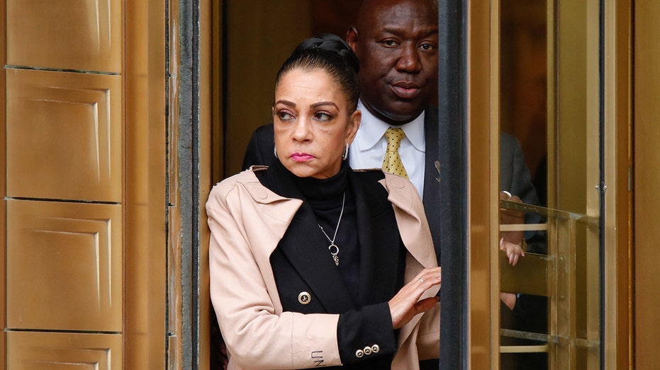 Kathryn Townsend Griffin in a khaki colored jacket and black blazer and sweater exits a revolving door at the New York Federal Court house with lawyer Ben Crump behind her