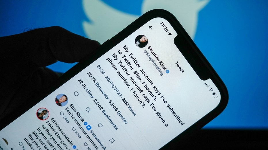 Tweets by Stephen King and Elon Musk are seen on a mobile cellphone